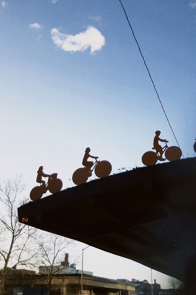 february 15, 2023: three sculptures of bicyclists silhouetted against the blue sky.